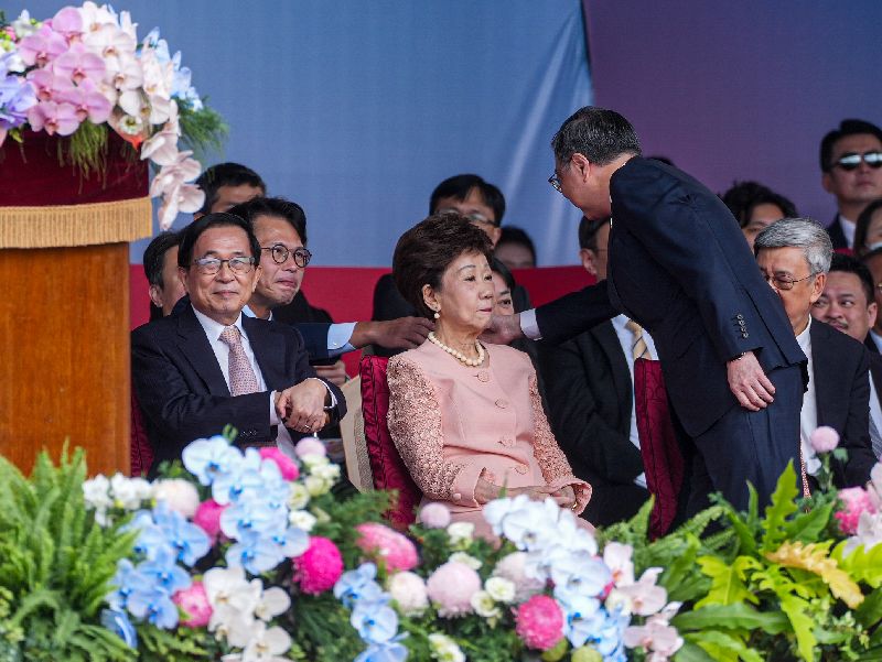 中華民國115年國慶大會10日上午在總統府前舉行,行政院長卓榮泰(前右,站者)與民眾黨主席黃國昌(後左)握手致意。前左為前總統陳水扁、前左2為前副總統呂秀蓮