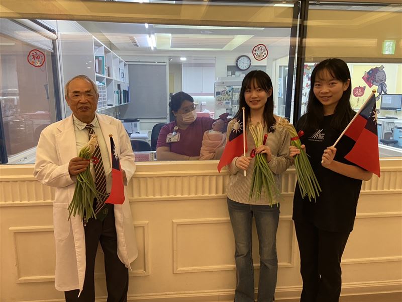茂盛醫院邀請20年前由李茂盛院長催生的大試管寶寶-黃氏姐妹,一起幫今年5點28分出生的「第一位」國慶寶寶送上青蔥,象徵聰明智慧。(圖/茂盛醫院提供)