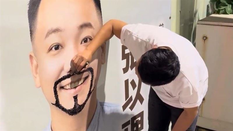 高雄市左楠區市議員候選人張以理，發現自己的競選看板出現劃損，利用行程空檔親自帶著畫筆前往，將另一邊的鬍子「補齊」。（圖／張以理提供）