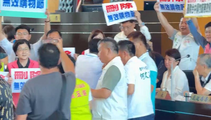 民進黨團議員高舉標語、衝到官員席前,要求刪除購物節3.9億預算。(圖/翻攝畫面)