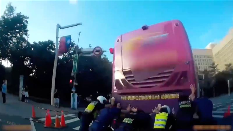 警方獲報到場後,由6名員警合力將故障遊覽車推離車道。(圖/翻攝畫面)