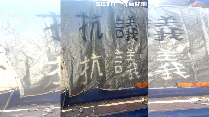用吊車吊起3樓高布條,上頭寫著「抗議」2字。(圖/翻攝畫面)