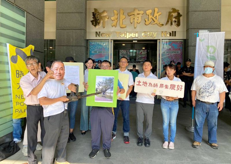 台灣樹人會秘書長潘翰疆(左)16日與護樹團體、公園團體至新北市府外陳情抗議,現場並上演砍樹行動劇,抗議板橋區望月公園計畫興建停車場。(台灣樹人會提供)