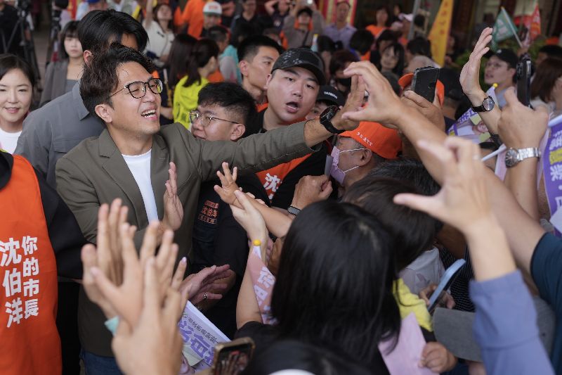 民進黨台北市長參選人沈伯洋(前左)17日在社子島坤天亭,出席祈安賜福遶境活動,與支持者擊掌互動