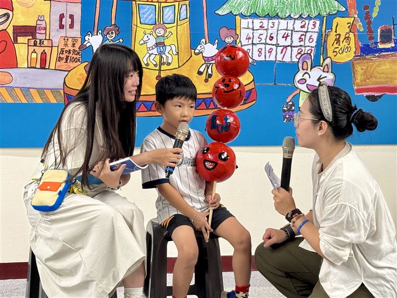 罹患「原發性肉鹼缺乏症」(PCD)的6歲男童吳秧宇特別從台中北上參加開幕式,與大家分享創作想法,並手持糖葫蘆造型道具,呼應畫作中的夜市主題。(圖/罕見疾病基金會提供)