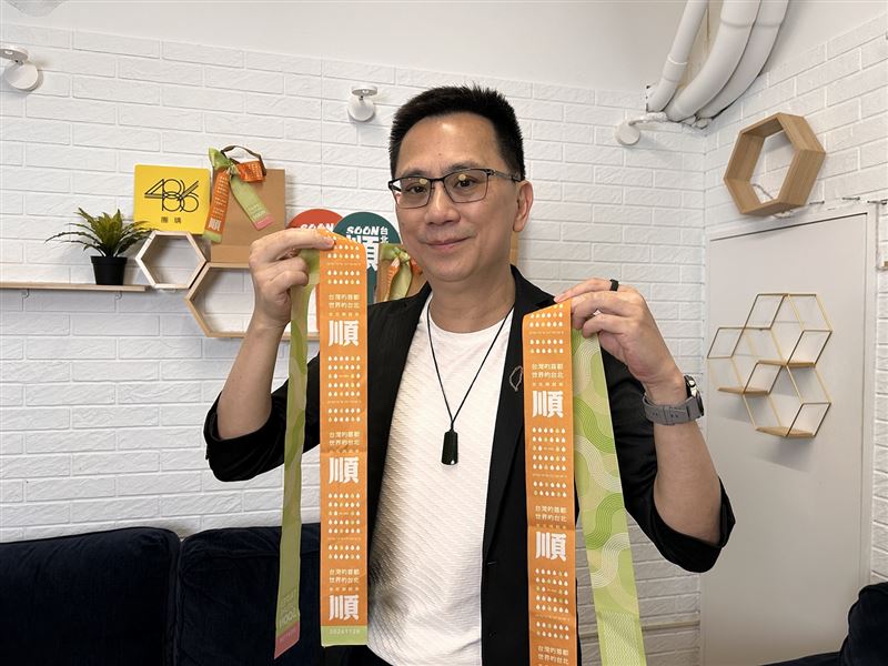 486先生手持沈伯洋特仕限量款飄帶，慶祝沈伯洋最新民調支持度領先蔣萬安。（圖／486先生提供）
