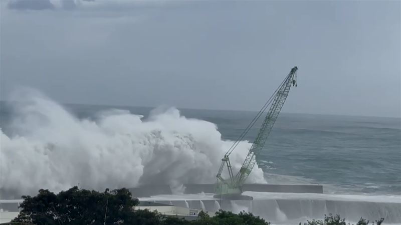 台東富岡漁港一輛吊掛消波塊的大型吊車遭巨浪擊沉入海。（圖／翻攝畫面）