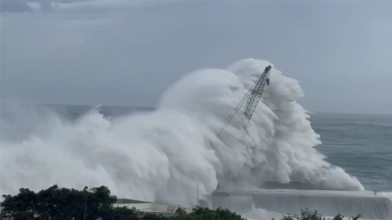 台東富岡漁港一輛吊掛消波塊的大型吊車遭巨浪擊沉入海。（圖／翻攝畫面）