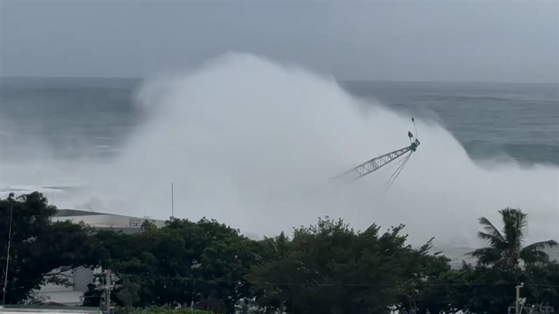台東富岡漁港一輛吊掛消波塊的大型吊車遭巨浪擊沉入海。（圖／翻攝畫面）