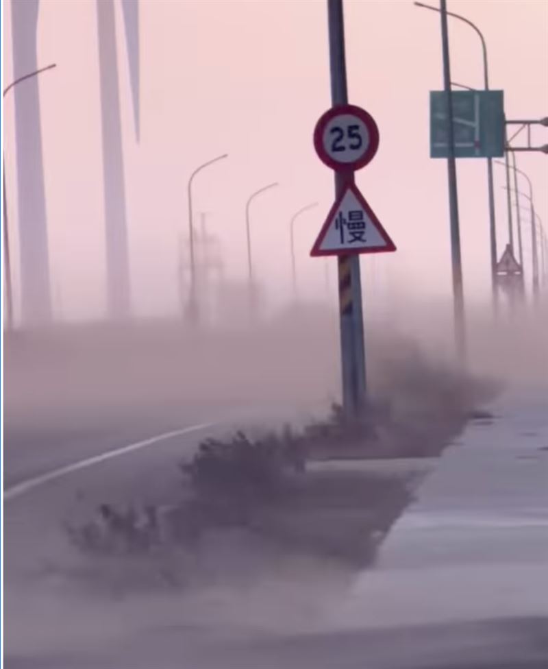 狂烈側風吹襲下，濱海空曠地的細沙被整片捲向空中，形成一道高聳的黃沙布幕，厚重的沙塵迅速覆蓋整個車道與路面。（圖／nate0430授權使用）