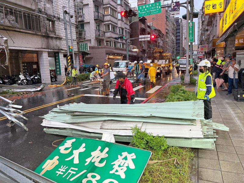 颱風薔琵帶來強風,新北市板橋區長江路二段一處住宅鐵皮遭掀翻掉落砸中汽車,幸無人傷亡。區公所隨即派遣工務單位到場協助切割拆除、清運。(板橋區公所提供)