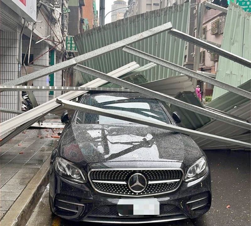 颱風薔琵來襲,新北市板橋區長江路上一處鐵皮屋頂遭強風掀翻掉落,砸中路旁轎車,所幸無人傷亡。(新北市海山警分局提供)