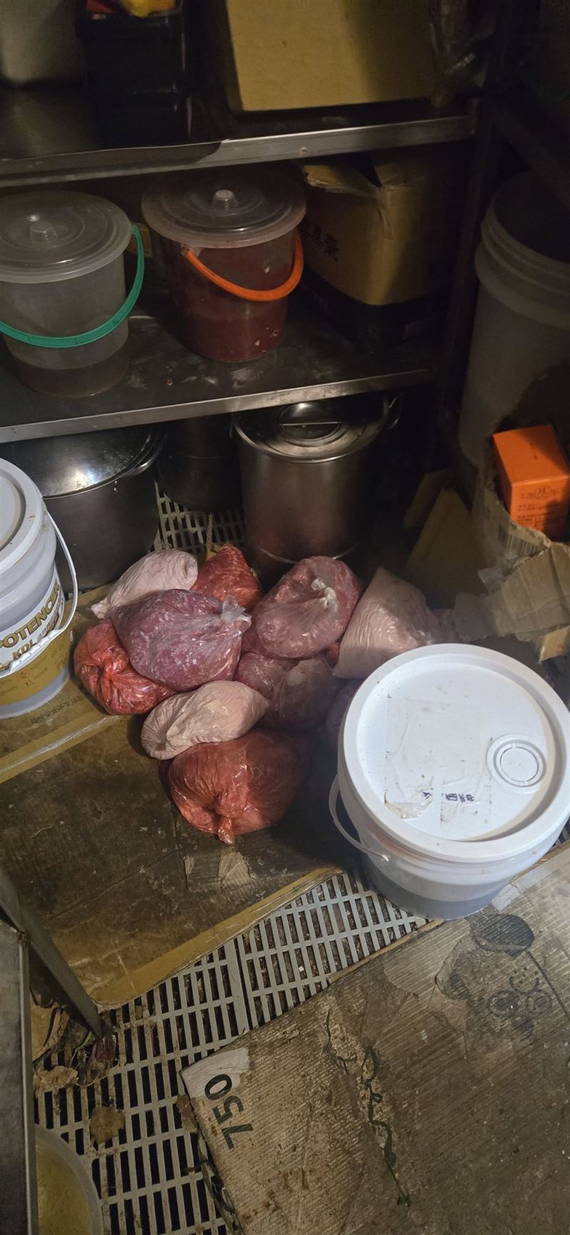大型塑膠袋、食材都直接堆疊在佈滿污漬與積垢的地板上。(圖/翻攝自爆料公社公開版)