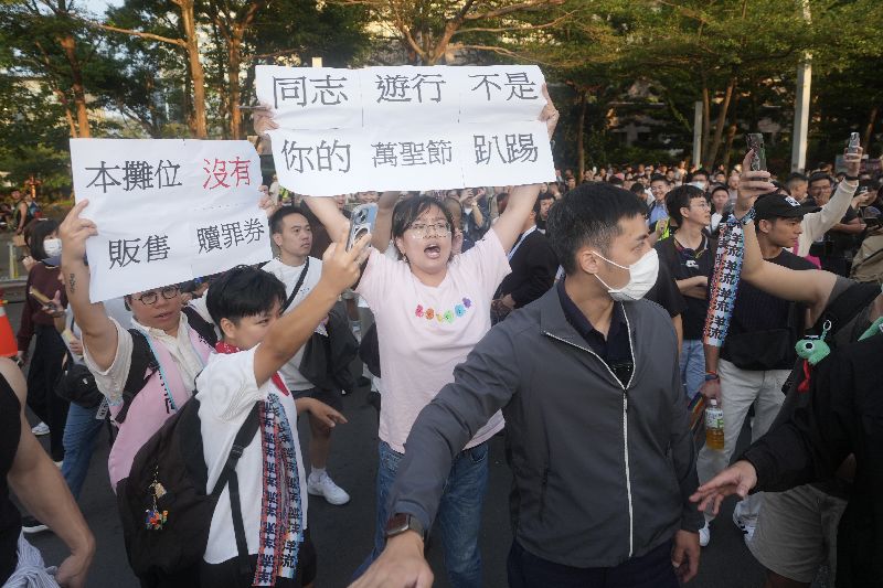 蔣萬安31日下午現身2026年第24屆台灣同志遊行現場，周邊則有民眾持標語表達抗議訴求。(圖／中央社）